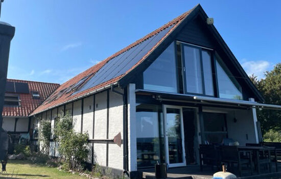 Integreret solcelleanlæg med batteri og sorte solceller på rødt tegl